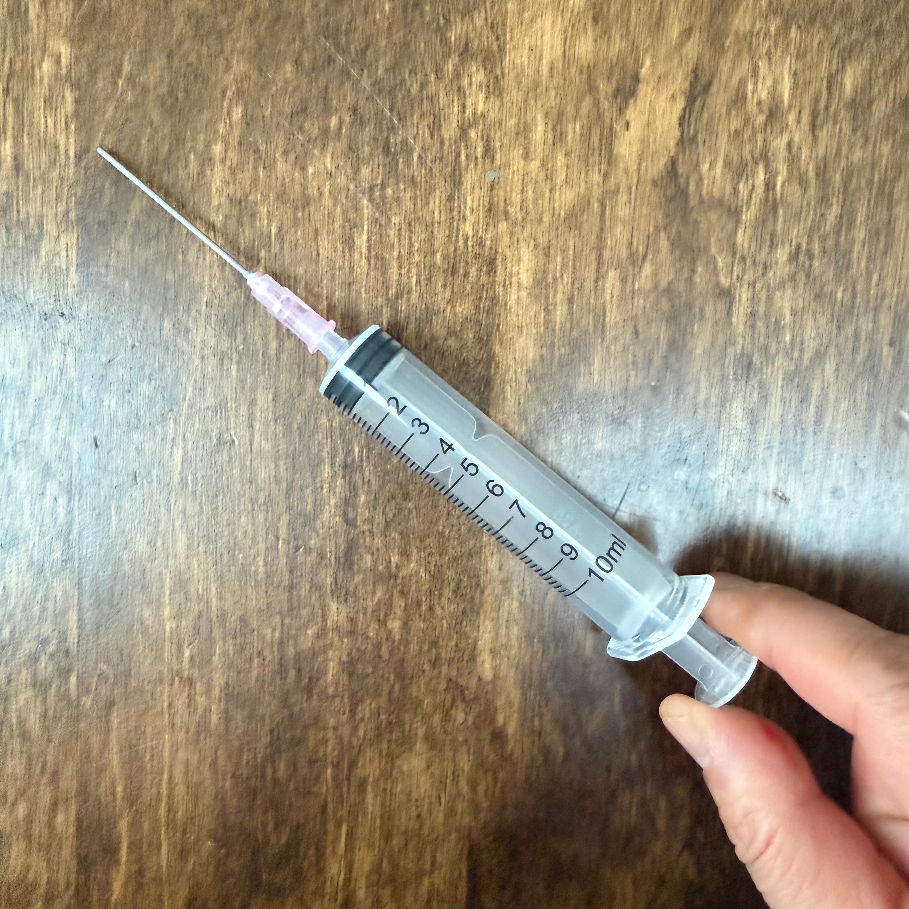Close-up of 10 mL ink syringe with blunt metal tip for refilling fountain pen cartridges