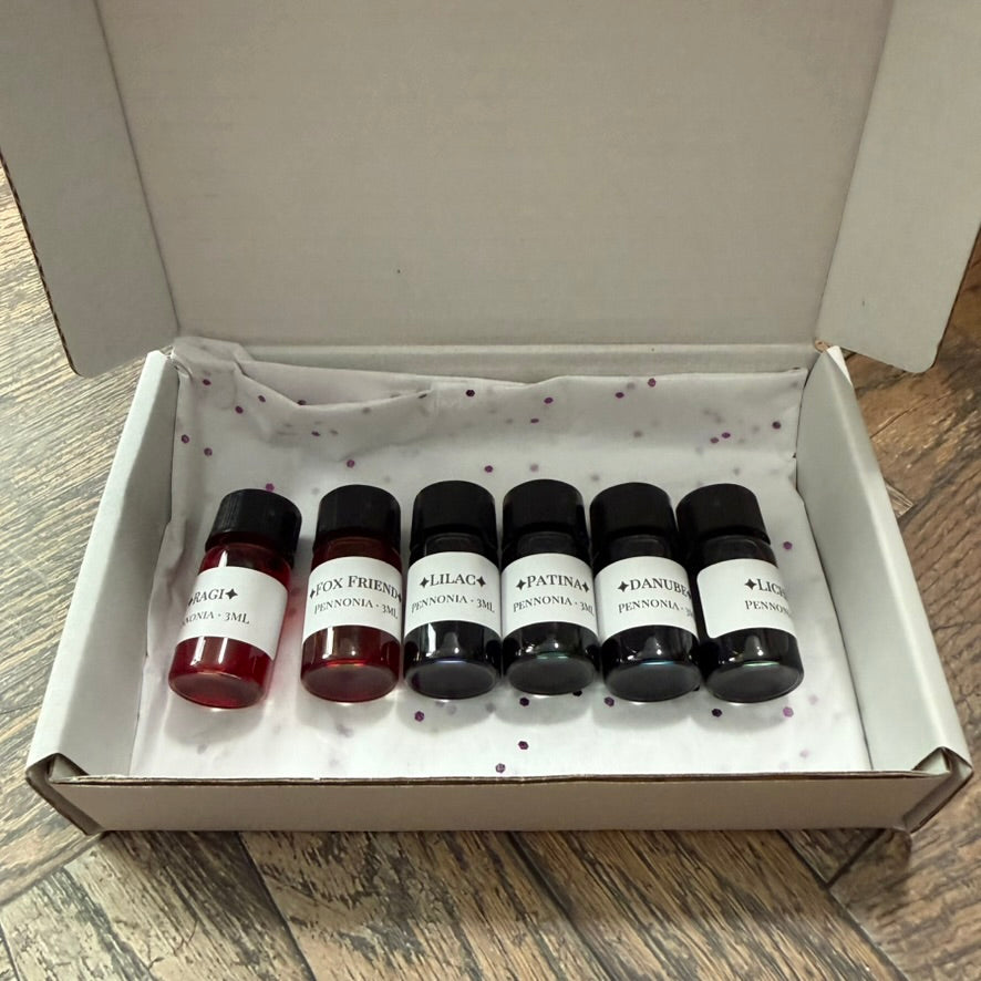 A Naturalist's Notebook gift set: six 3 mL glass vials of Pennonia ink in an open white gift box with tissue and purple confetti
