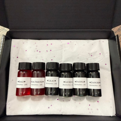 A Naturalist's Notebook gift set: six 5 mL glass vials of Pennonia ink on white tissue with purple confetti in a gift box
