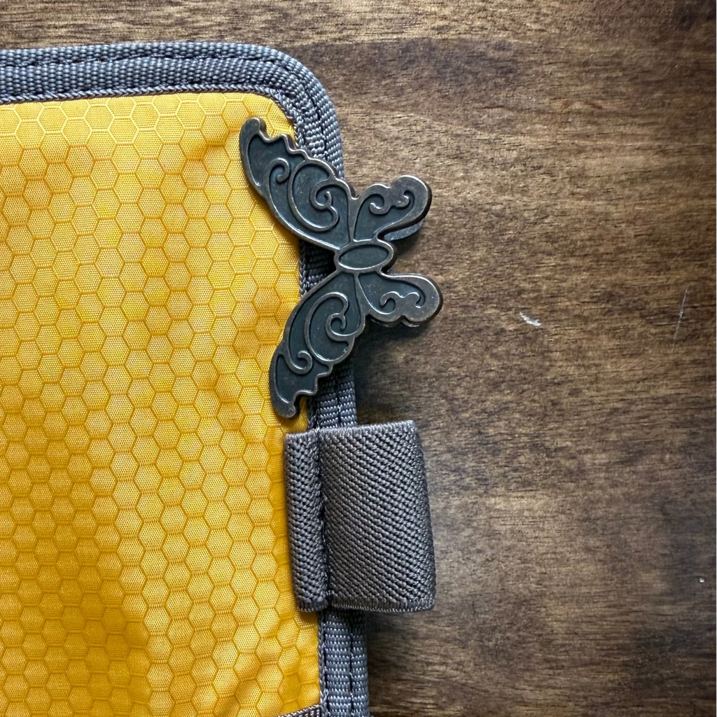 Antique brass butterfly clip attached to the edge of a notebook case