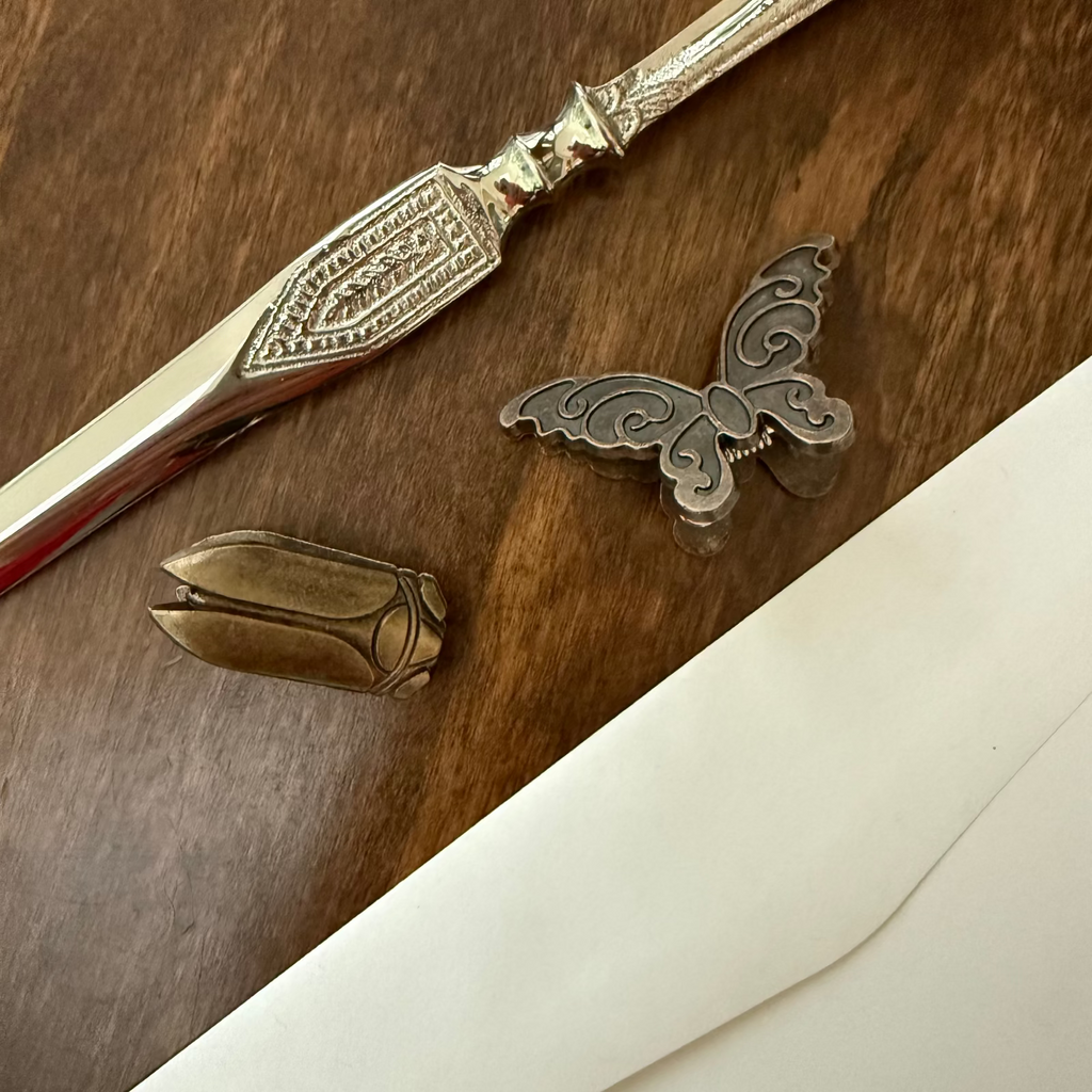 Antique brass butterfly and beetle journal clips styled with writing desk objects