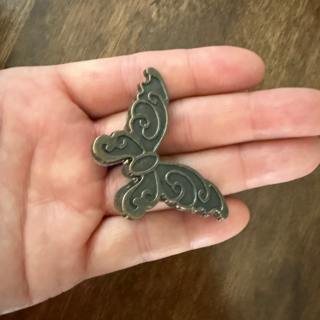 Antique brass butterfly journal clip shown in hand for scale