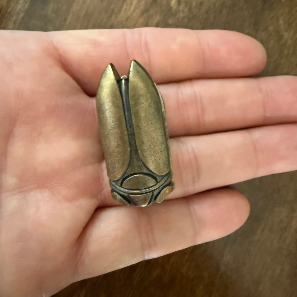Small antique bronze beetle journal clip shown in hand for scale
