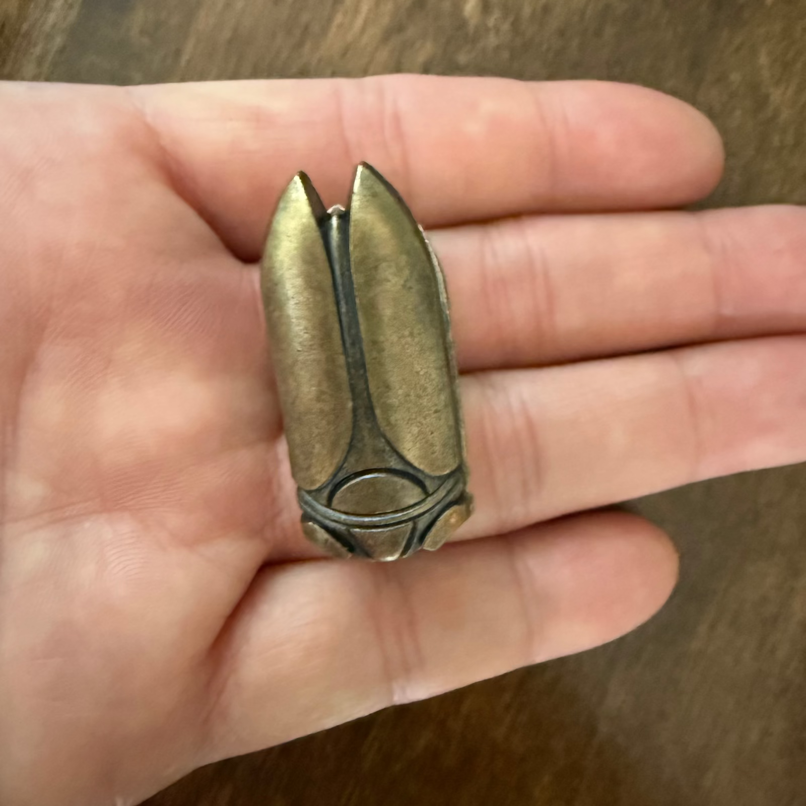 Small antique bronze beetle journal clip shown in hand for scale