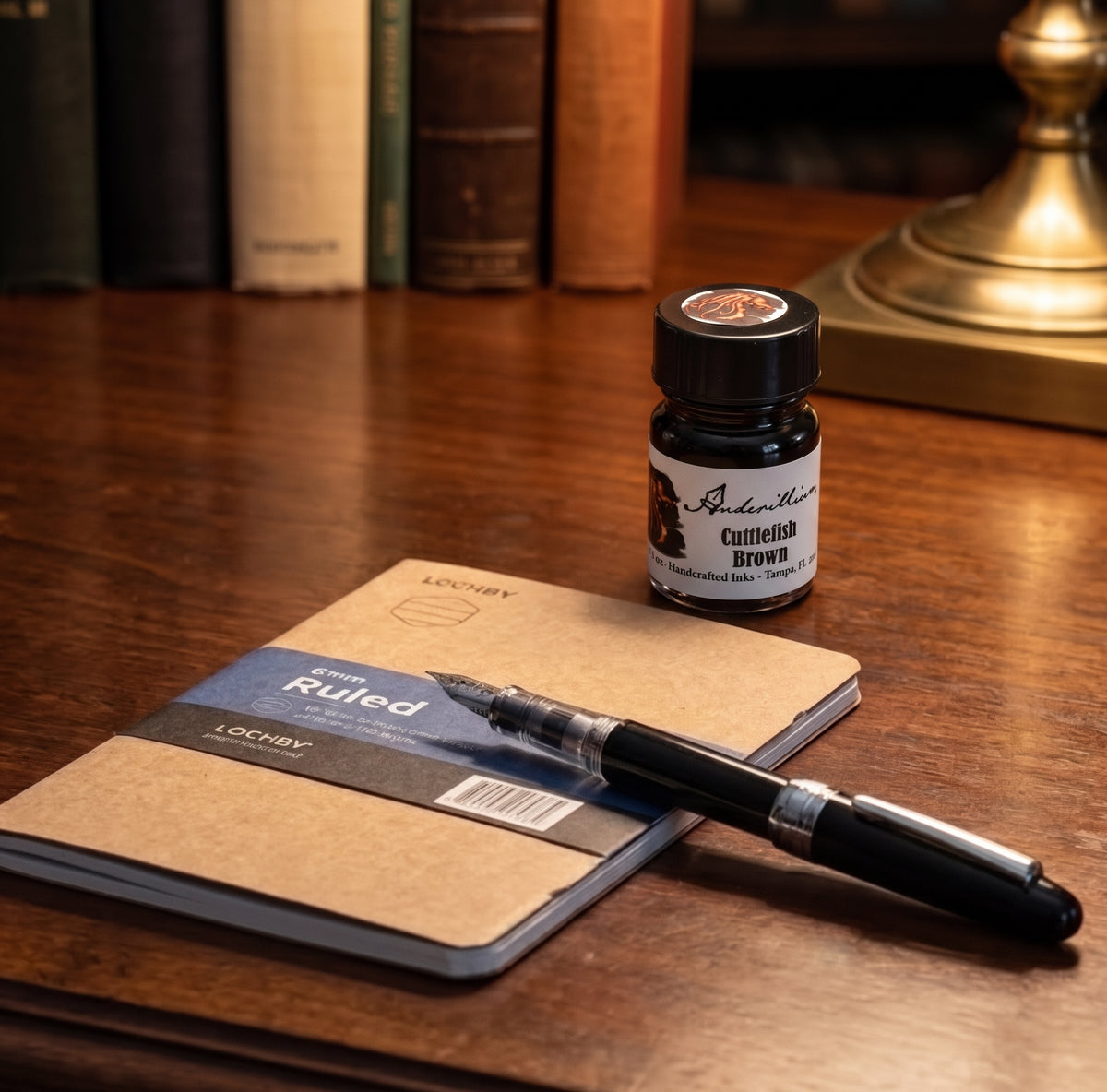 The Archive Starter Kit with a black Platinum Plaisir fountain pen, Lochby A5 ruled notebook, and Anderillium Cuttlefish Brown ink arranged on a wooden writing desk.