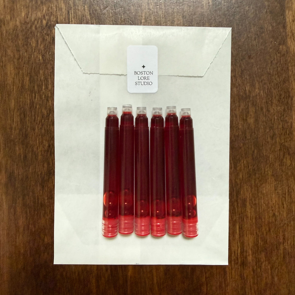 Six red short international fountain pen ink cartridges with Boston Lore Studio glassine envelope