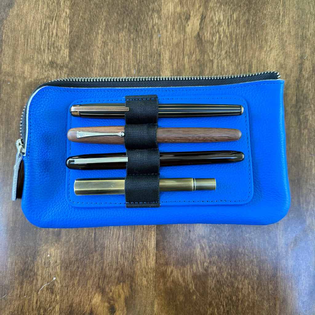 Four pens secured horizontally in the removable insert on the blue cowhide leather case.