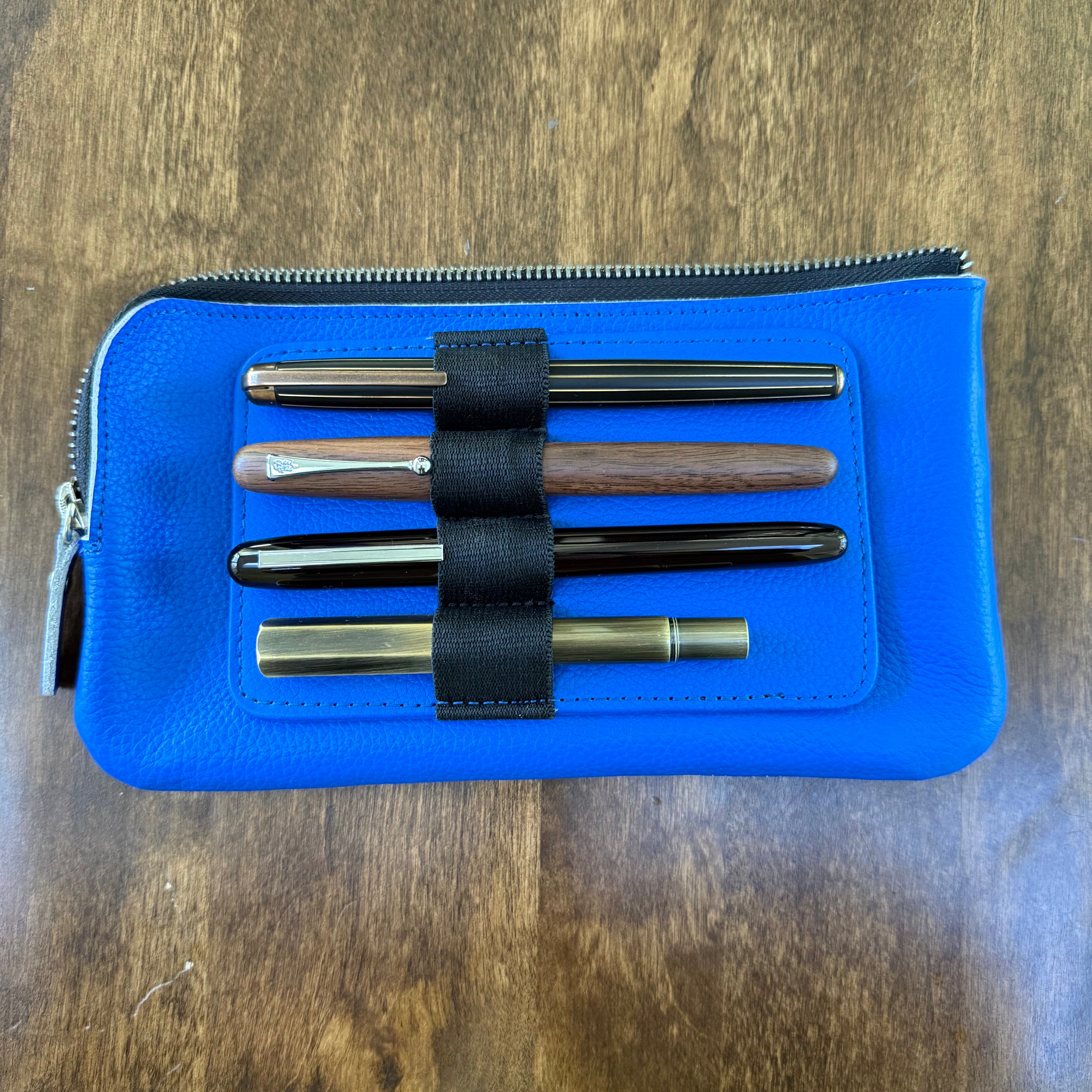 Four pens secured horizontally in the removable insert on the blue cowhide leather case.