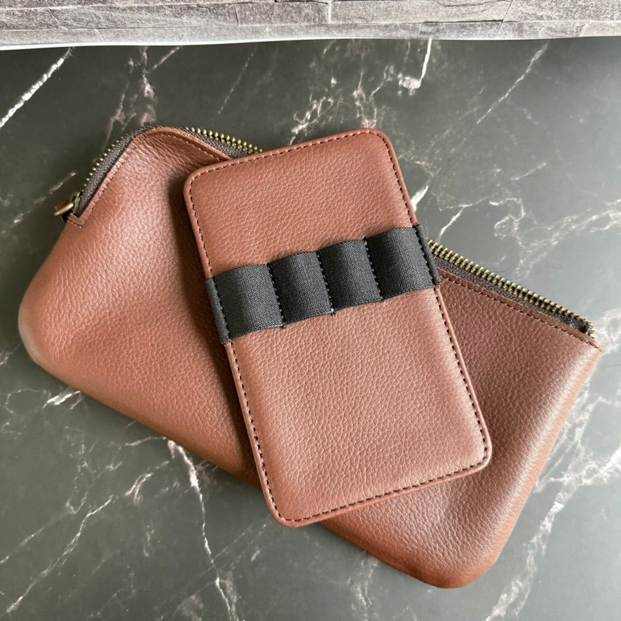 Empty four-pen leather insert with black elastic loops lying on the espresso brown cowhide zipper case