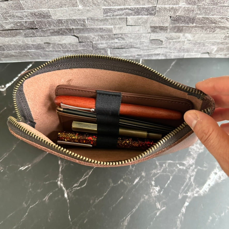 Inside view of the unzipped espresso brown pen case, with the leather pen insert and four pens tucked into the main compartment