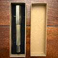 Compact brushed brass pocket fountain pen presented in a kraft paper box with black insert