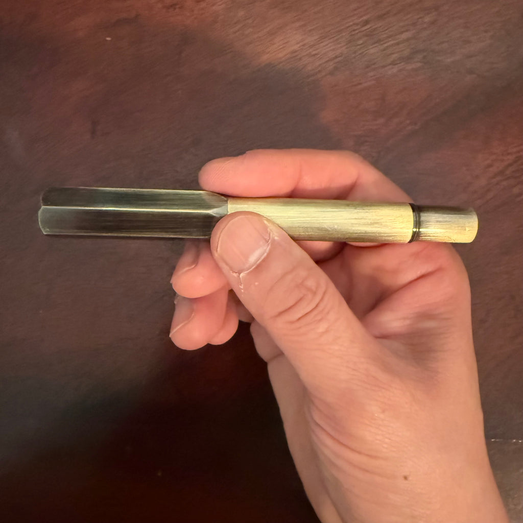 Compact brushed brass pocket fountain pen presented in a kraft paper box with black insert.
