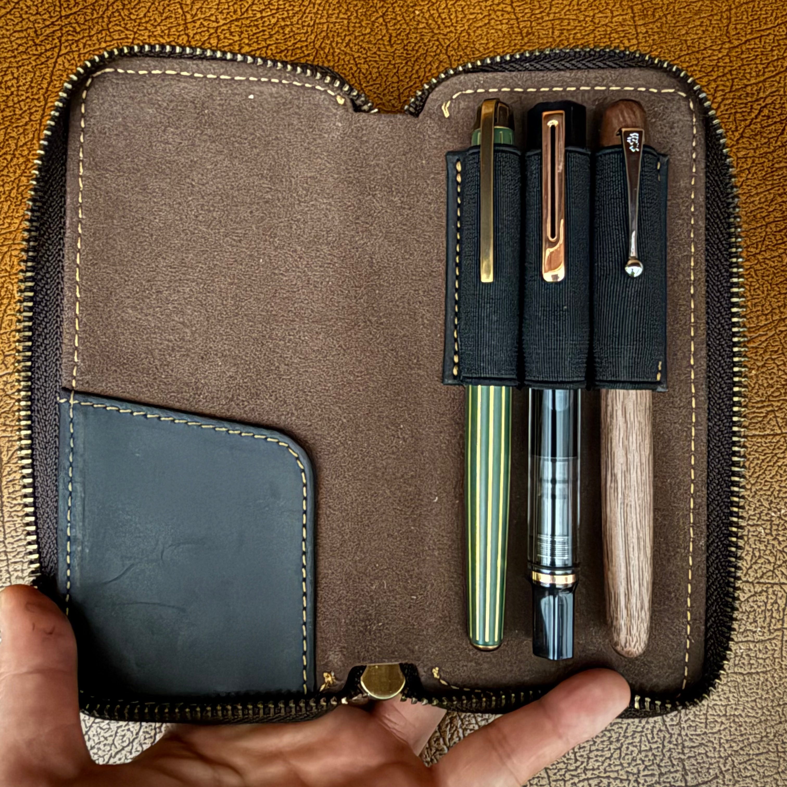 Open black leather 3-pen fountain pen case holding three pens