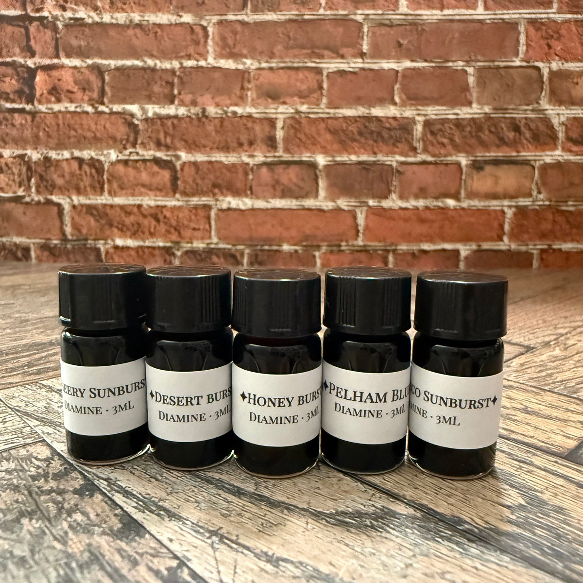 Five 3 mL glass vials of Diamine Guitar series ink labeled Cherry Sunburst, Desert Burst, Honey Burst, Pelham Blue and Tobacco Sunburst