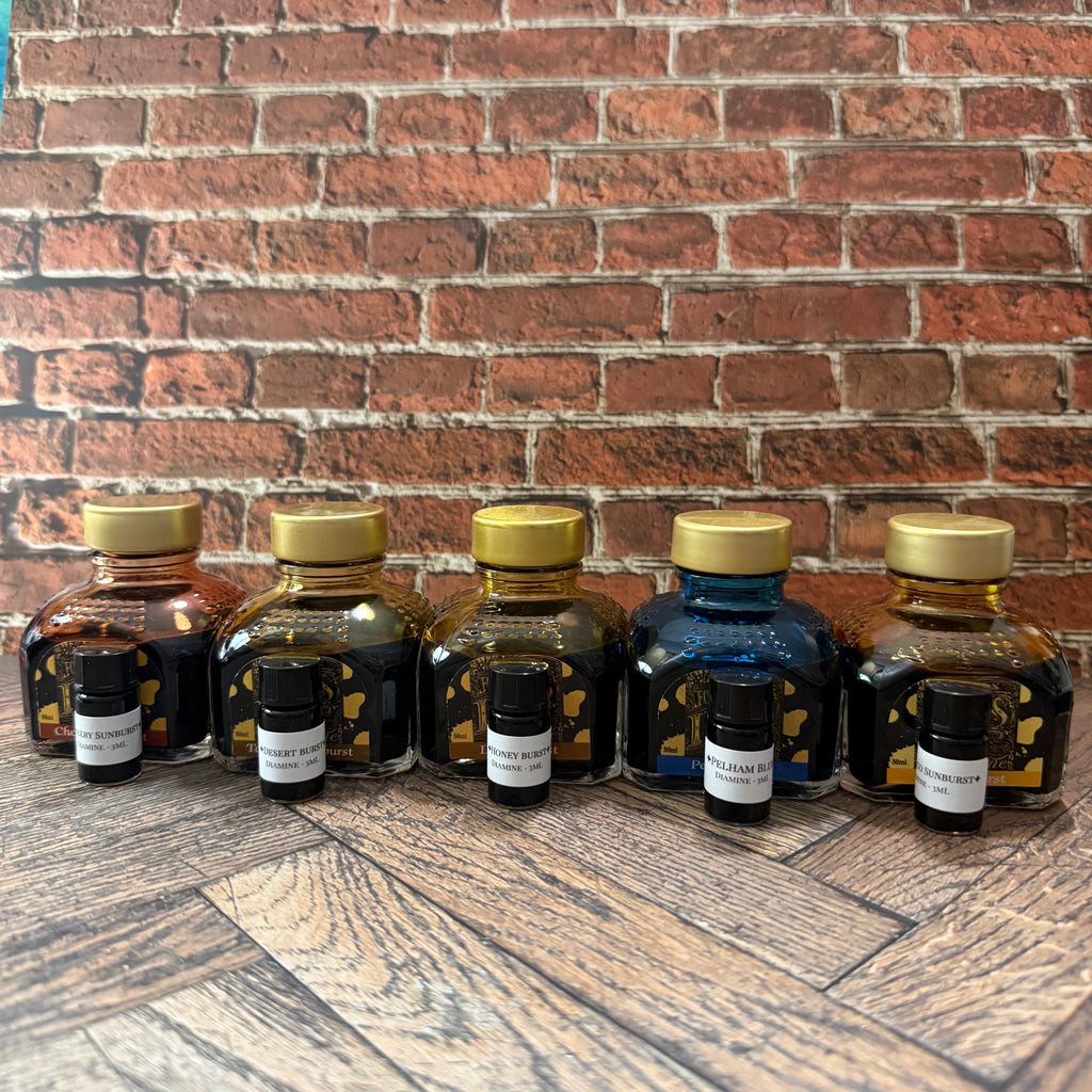 Five Diamine Guitar series 80 mL ink bottles with a 3 mL sample vial in front of each (bottles not included)