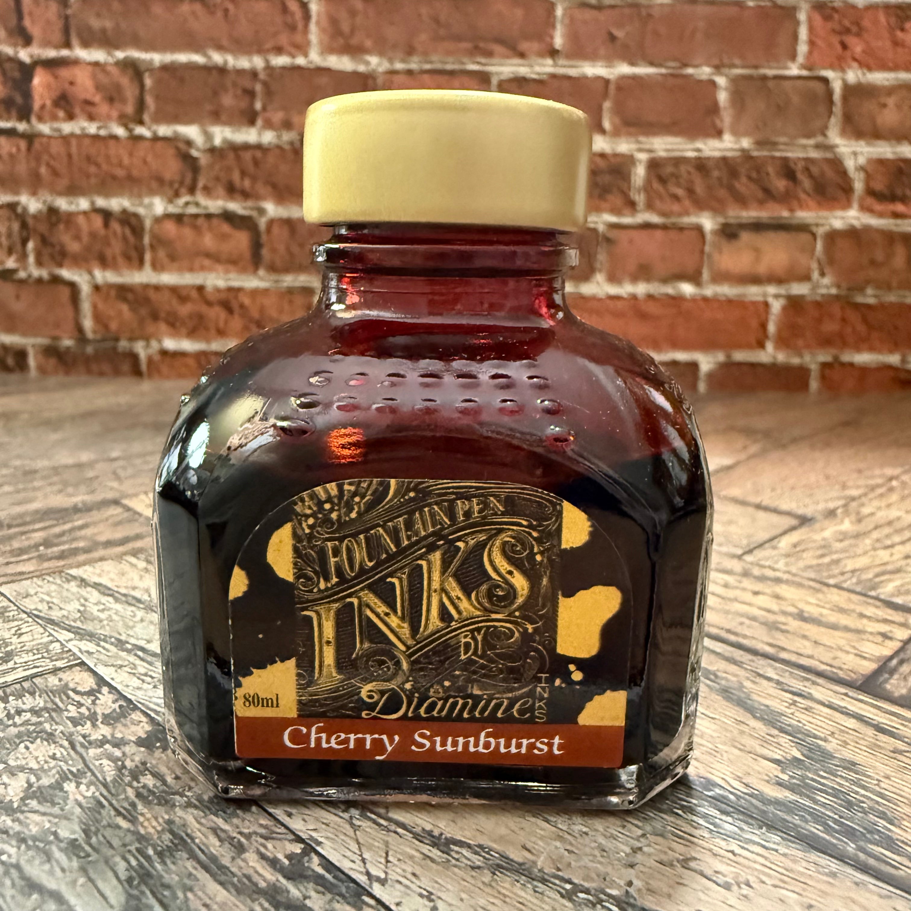 Diamine Cherry Sunburst red-brown fountain pen ink in an 80 mL glass bottle with a gold cap