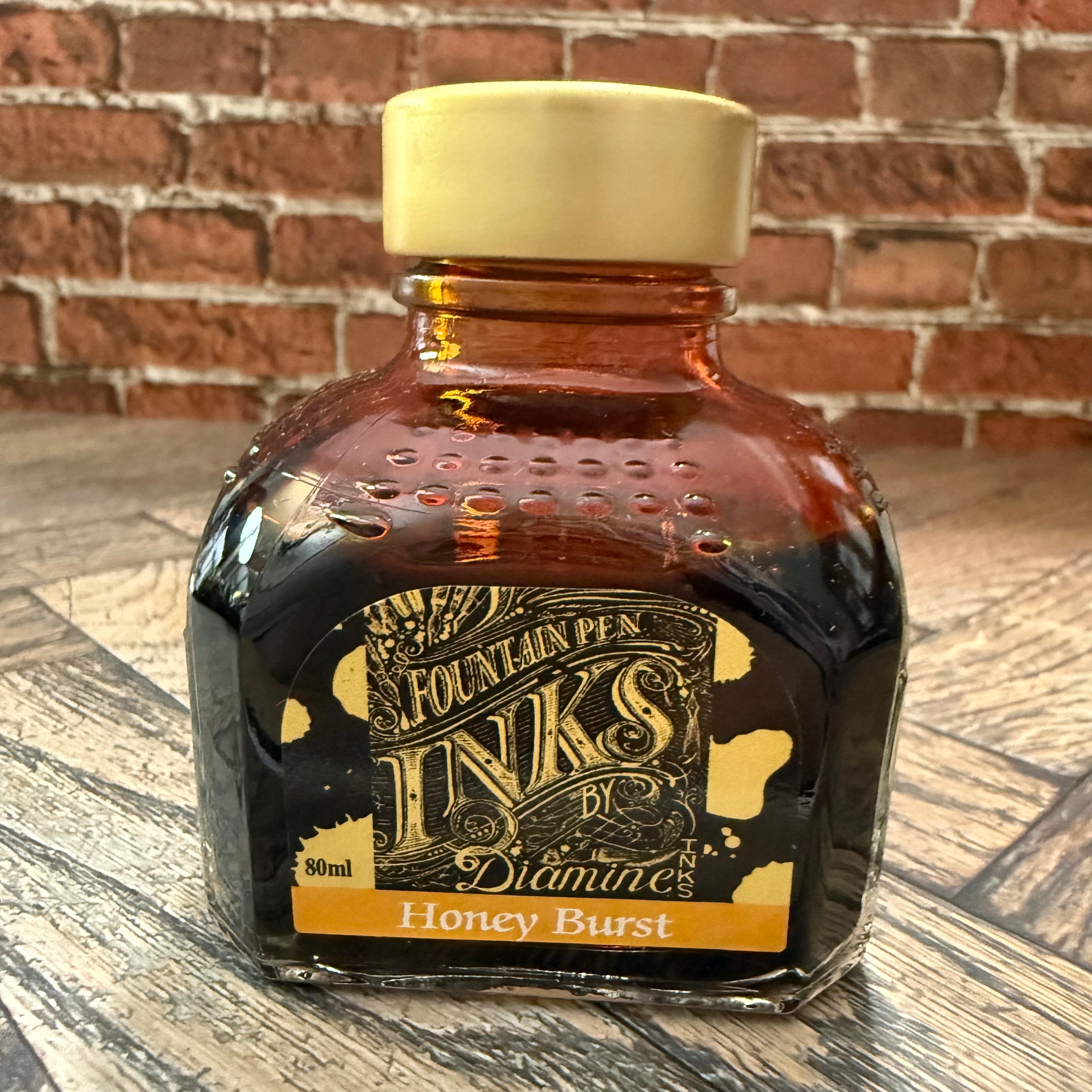 Diamine Honey Burst amber fountain pen ink in an 80 mL glass bottle with a gold cap