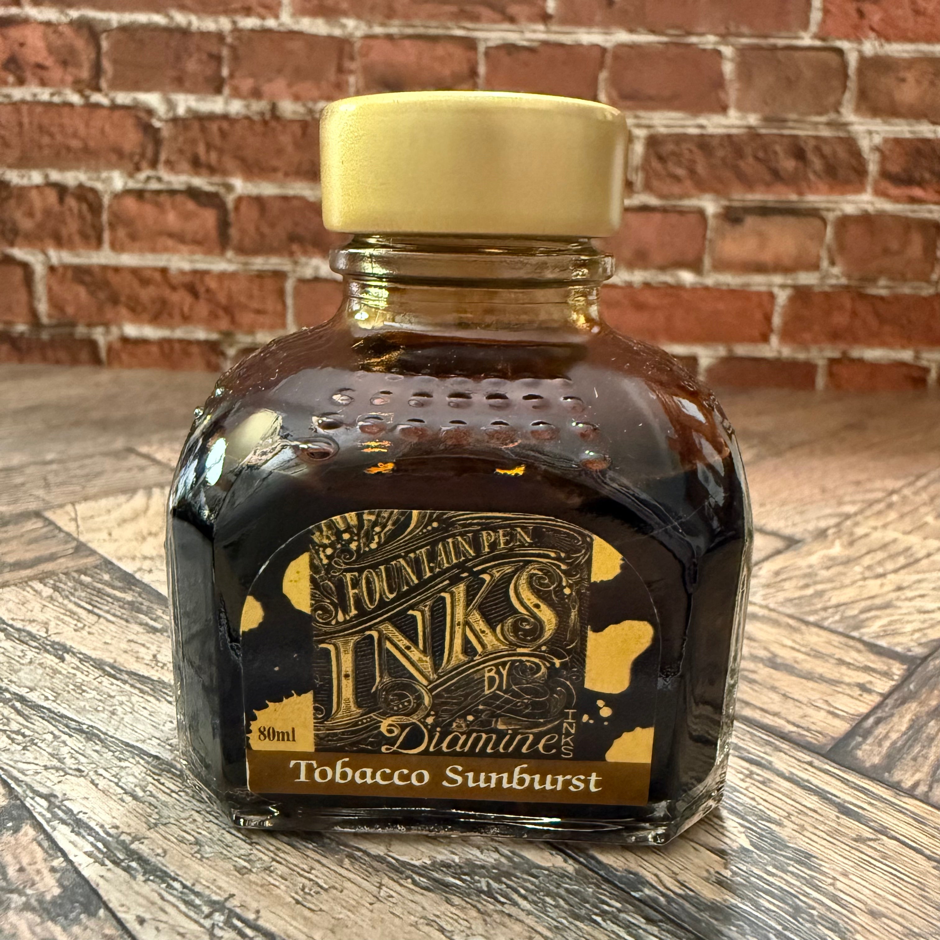 Diamine Tobacco Sunburst brown fountain pen ink in an 80 mL glass bottle with a gold cap