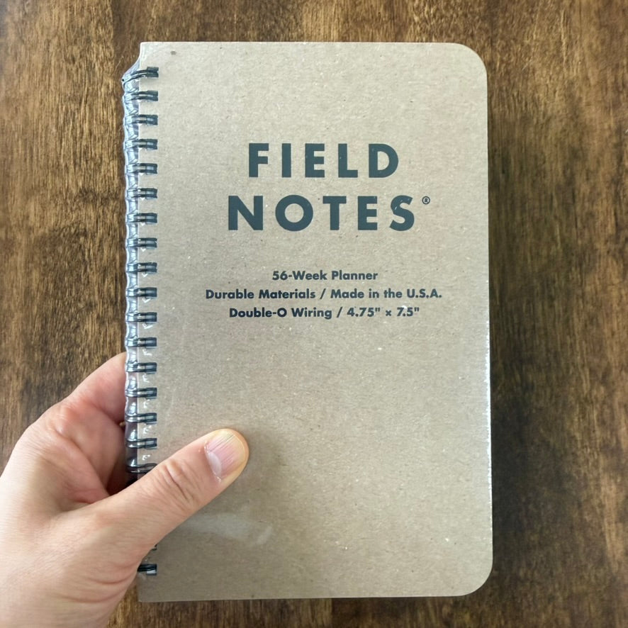Field Notes 56-Week Undated Planner held in one hand, showing its 4¾ × 7½ inch size and wire-bound kraft cover