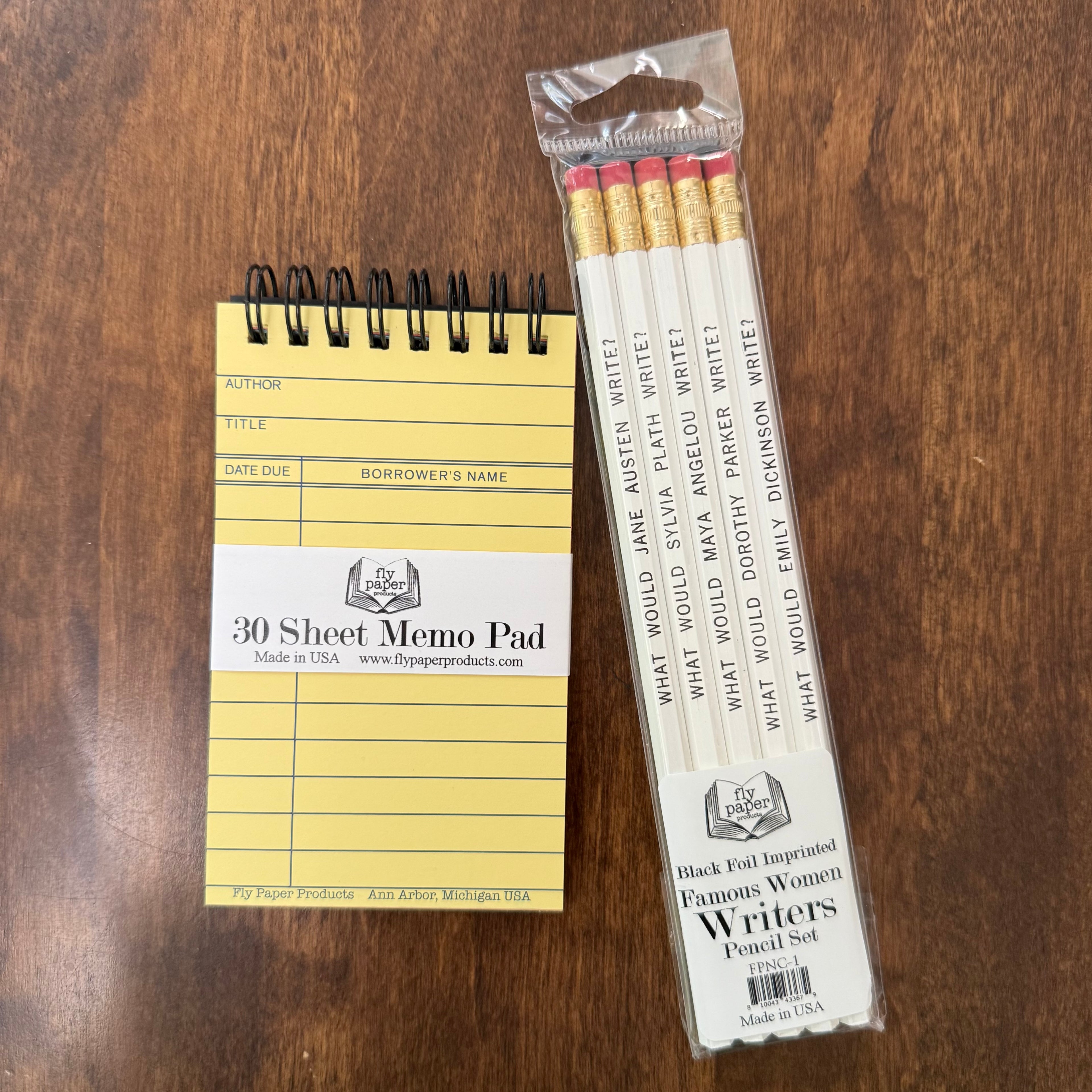 Famous Women Writers Pencil Set by Fly Paper Products beside a vintage library card memo pad on a wooden writing desk.