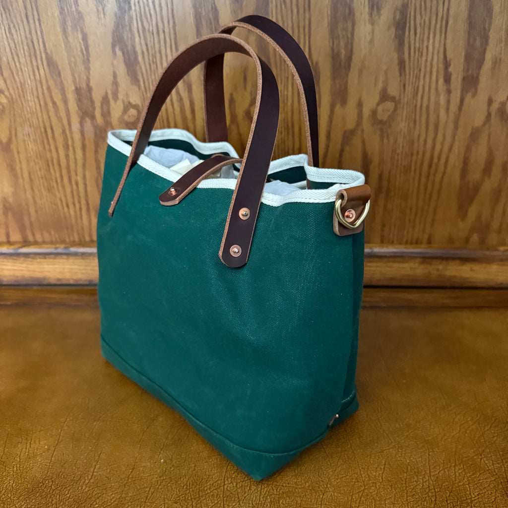 Side view showing the wide base of the General Knot waxed canvas mini tote in Tennis Green