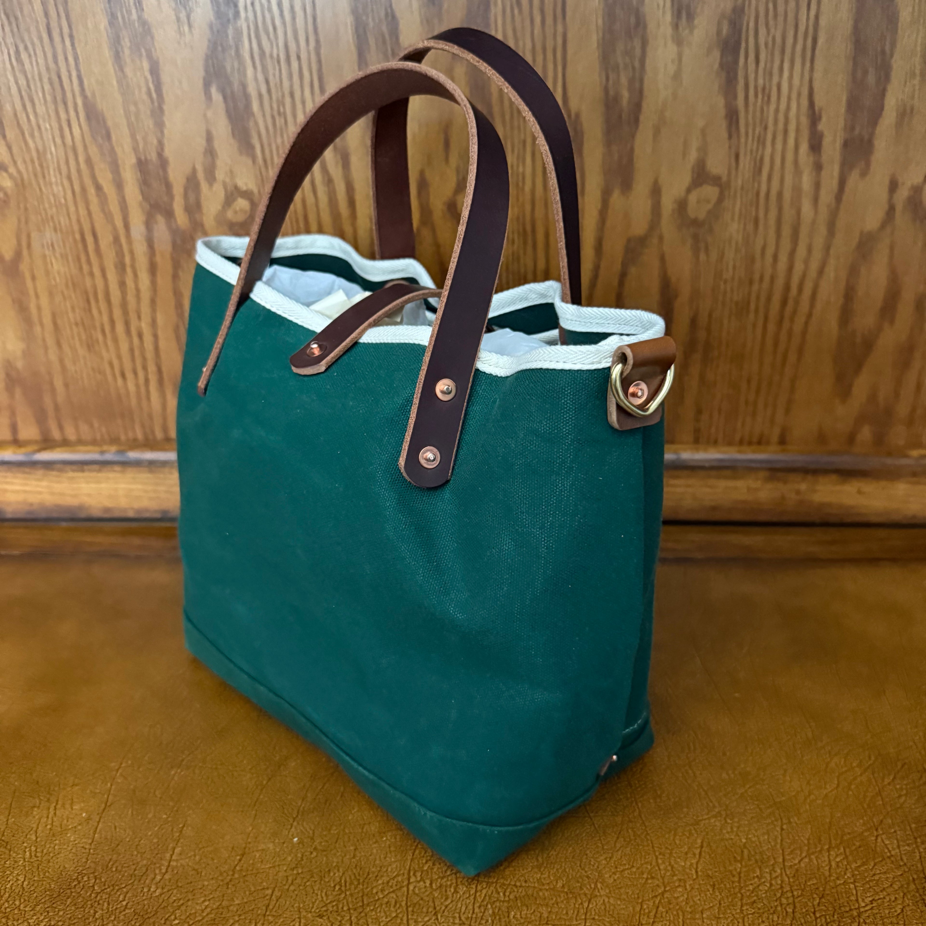 Side view showing the wide base of the General Knot waxed canvas mini tote in Tennis Green