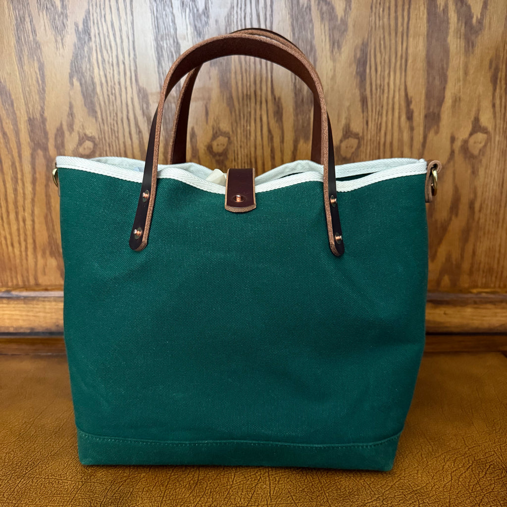 Three-quarter view of the General Knot Tennis Green waxed canvas mini tote