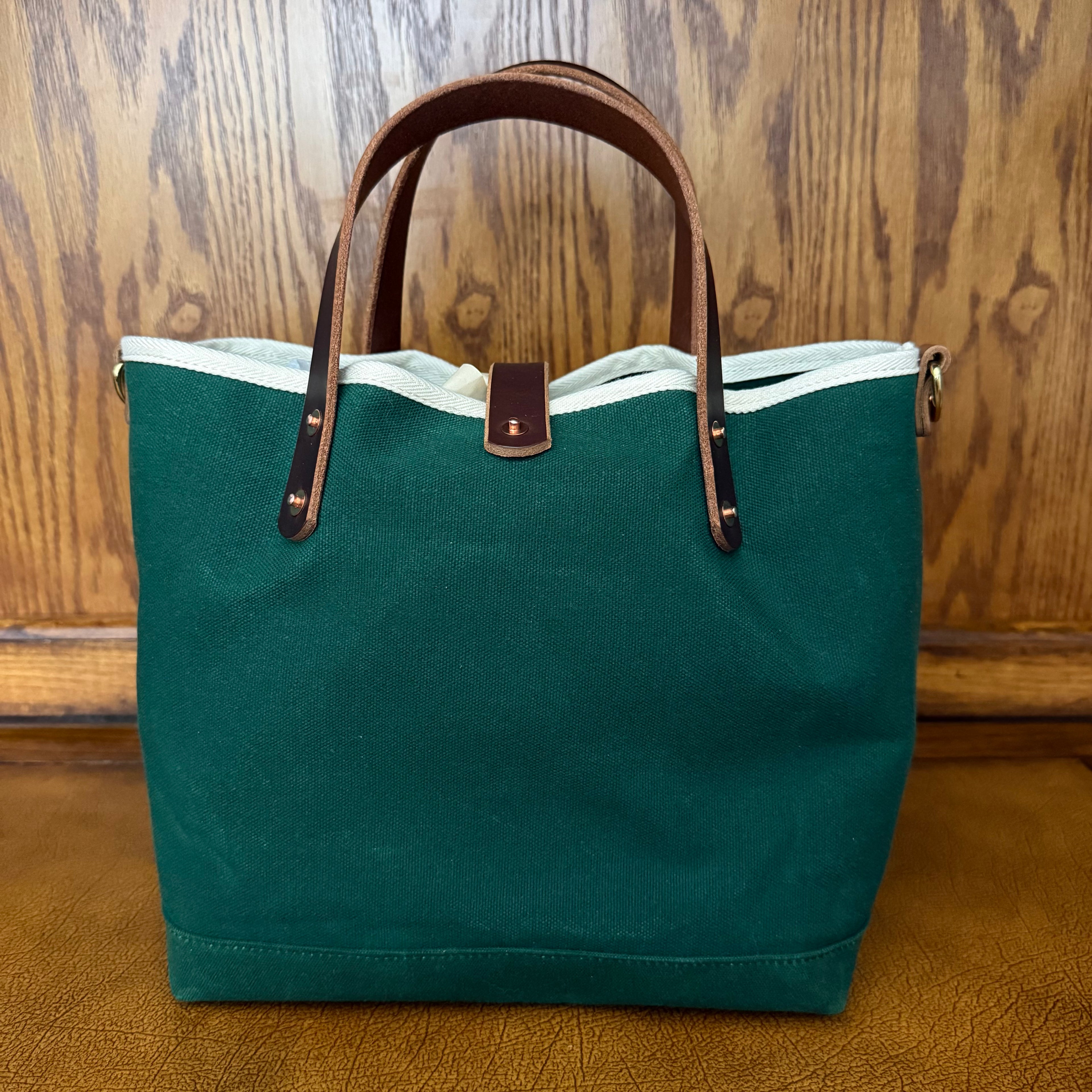 Three-quarter view of the General Knot Tennis Green waxed canvas mini tote