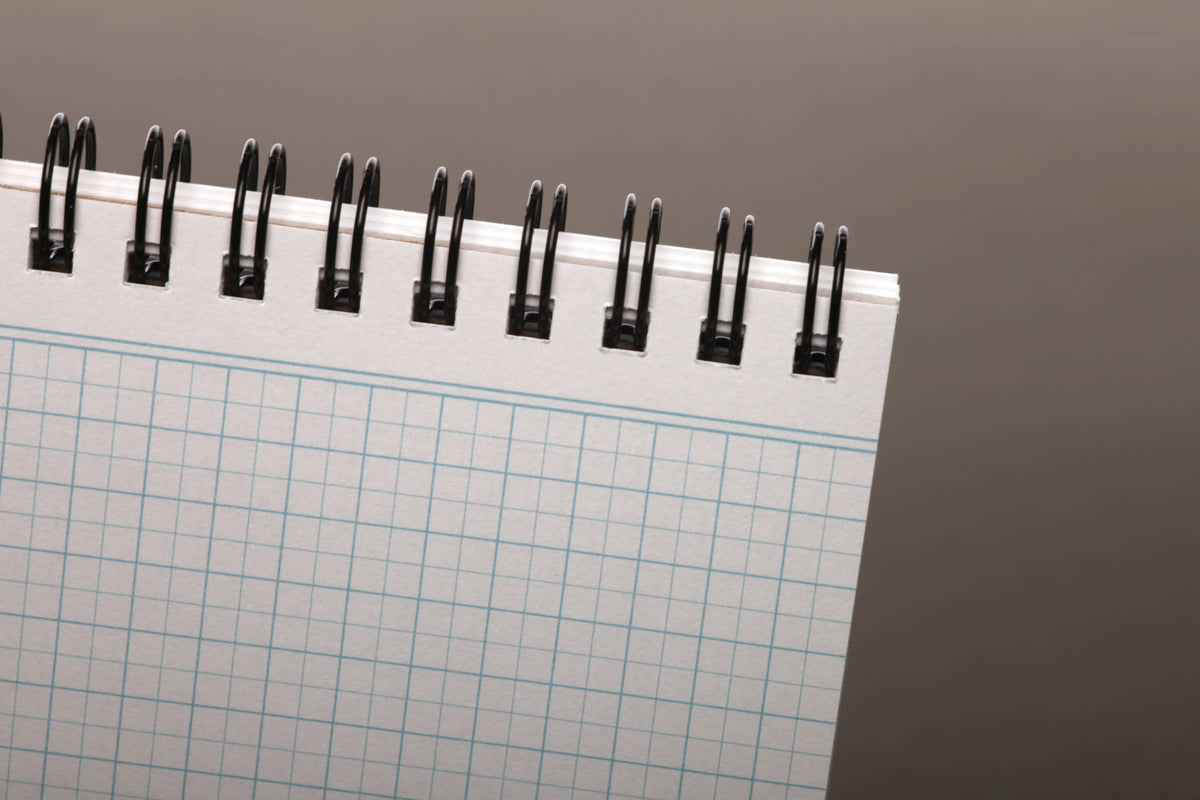 Graph paper pages under the spiral binding of a Field Notes Heavy Duty notebook