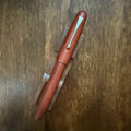 Jinhao 9035 Rosewood fountain pen capped on a wooden desk
