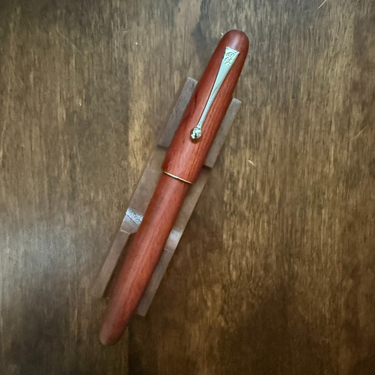 Jinhao 9035 Rosewood fountain pen capped on a wooden desk