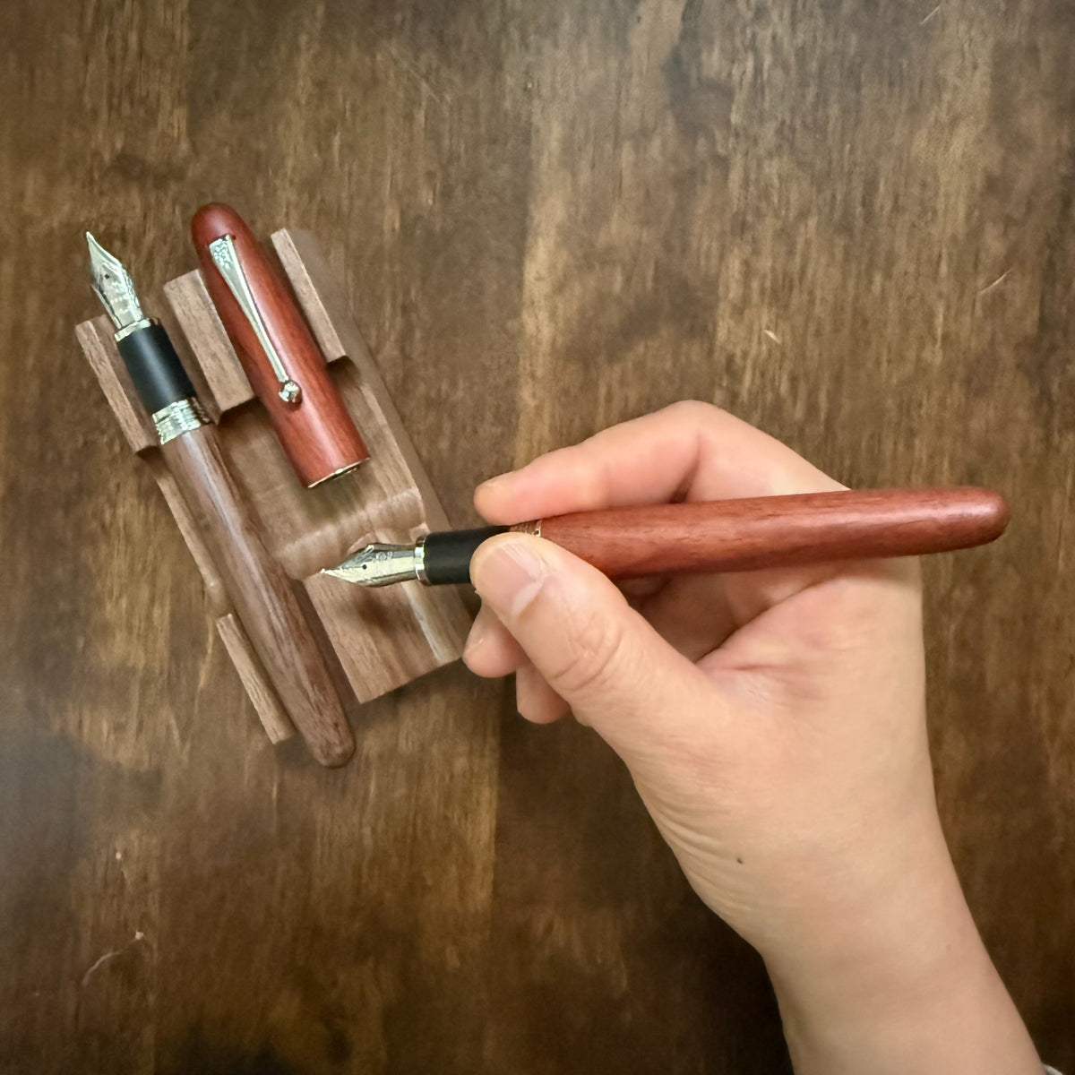 Jinhao 9035 Rosewood fountain pen uncapped and held in the writing position