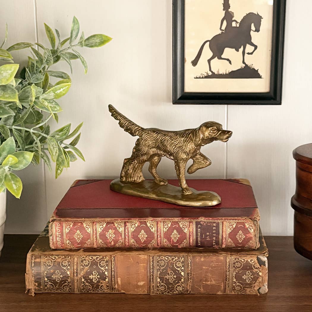 Brass pointer dog paperweight displayed on a stack of decorative books