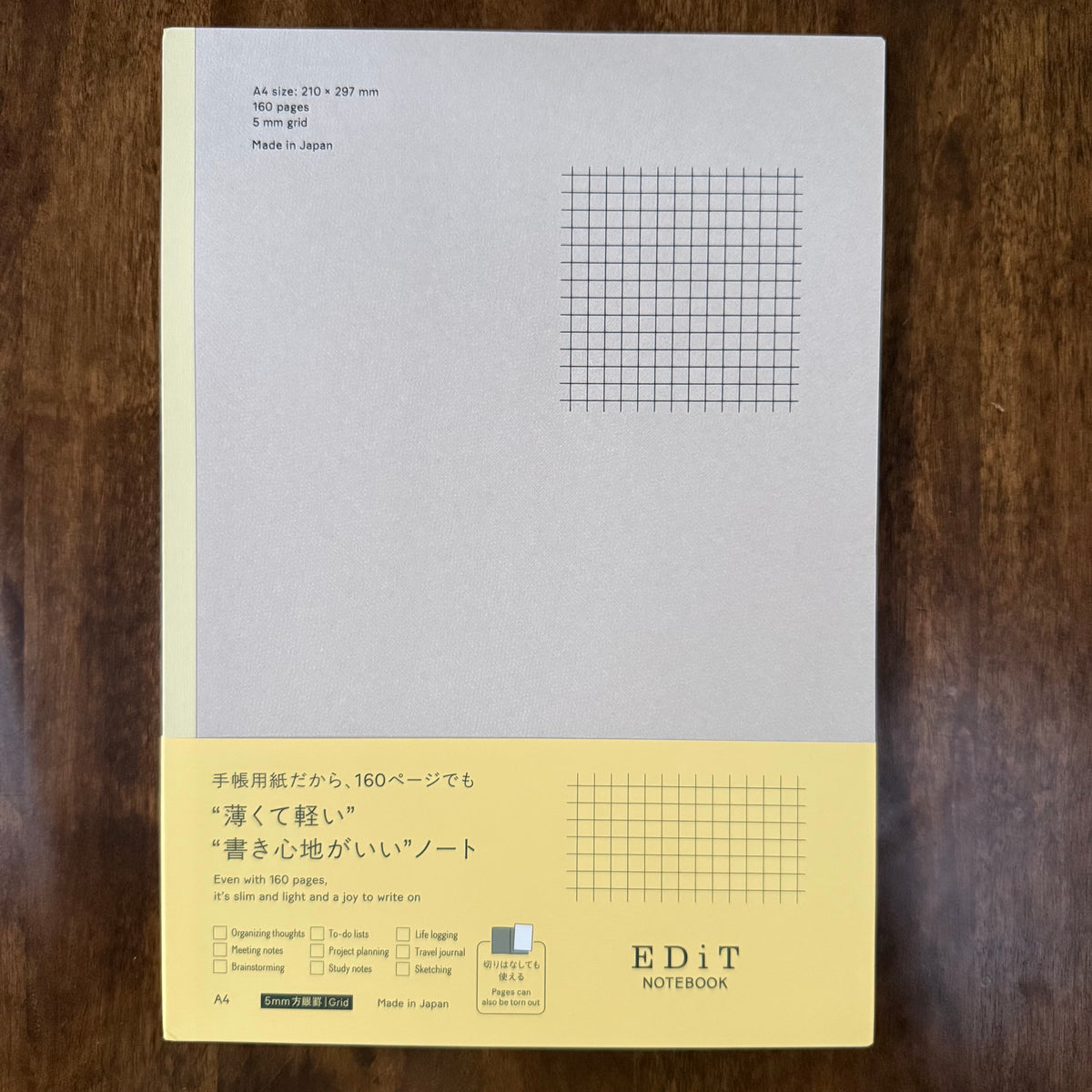 MARK’S EDiT A4 lightweight 5 mm grid notebook with a pale gray cover, yellow spine, and yellow paper band on a wooden surface.