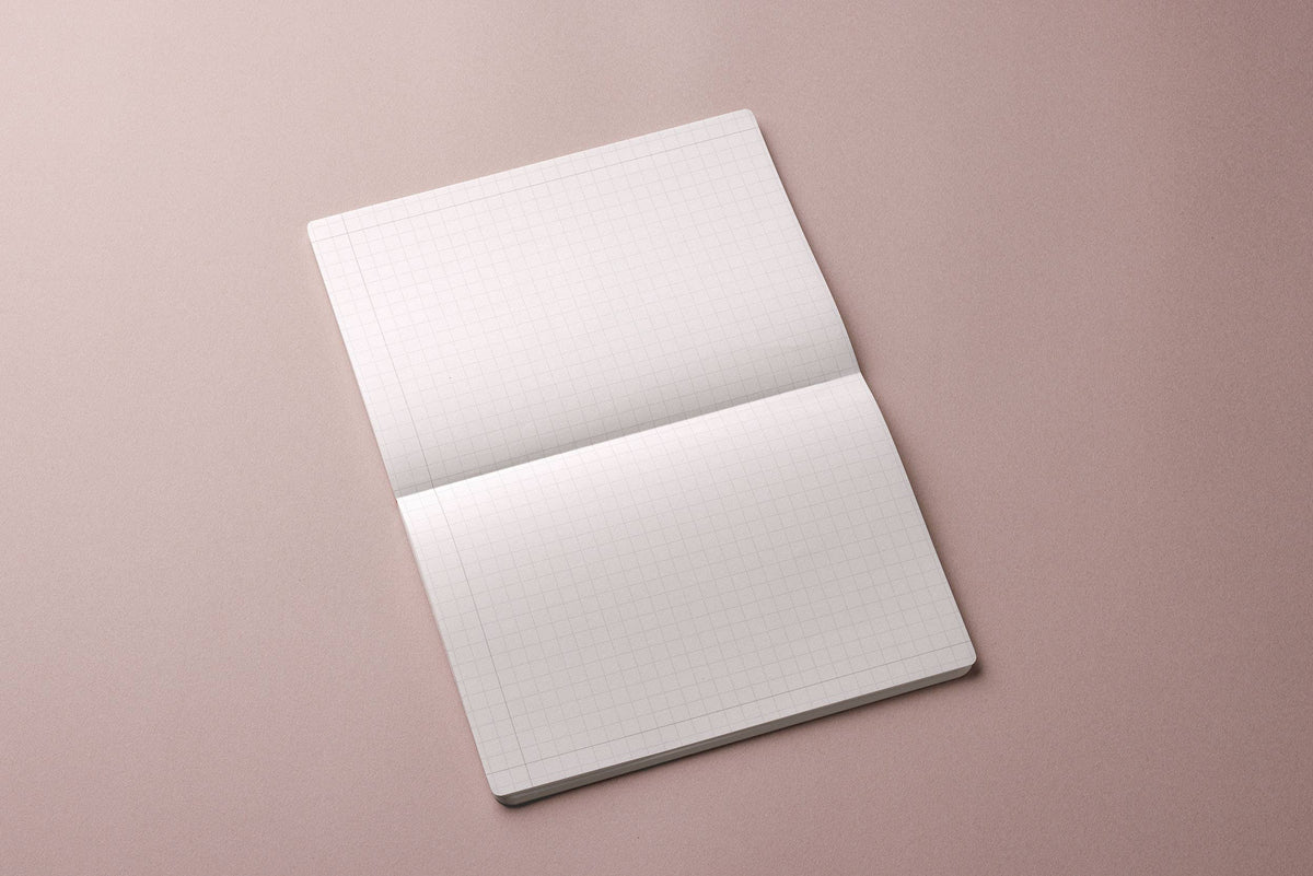 MARK’S EDiT A4 grid notebook opened in landscape orientation on a muted pink background.