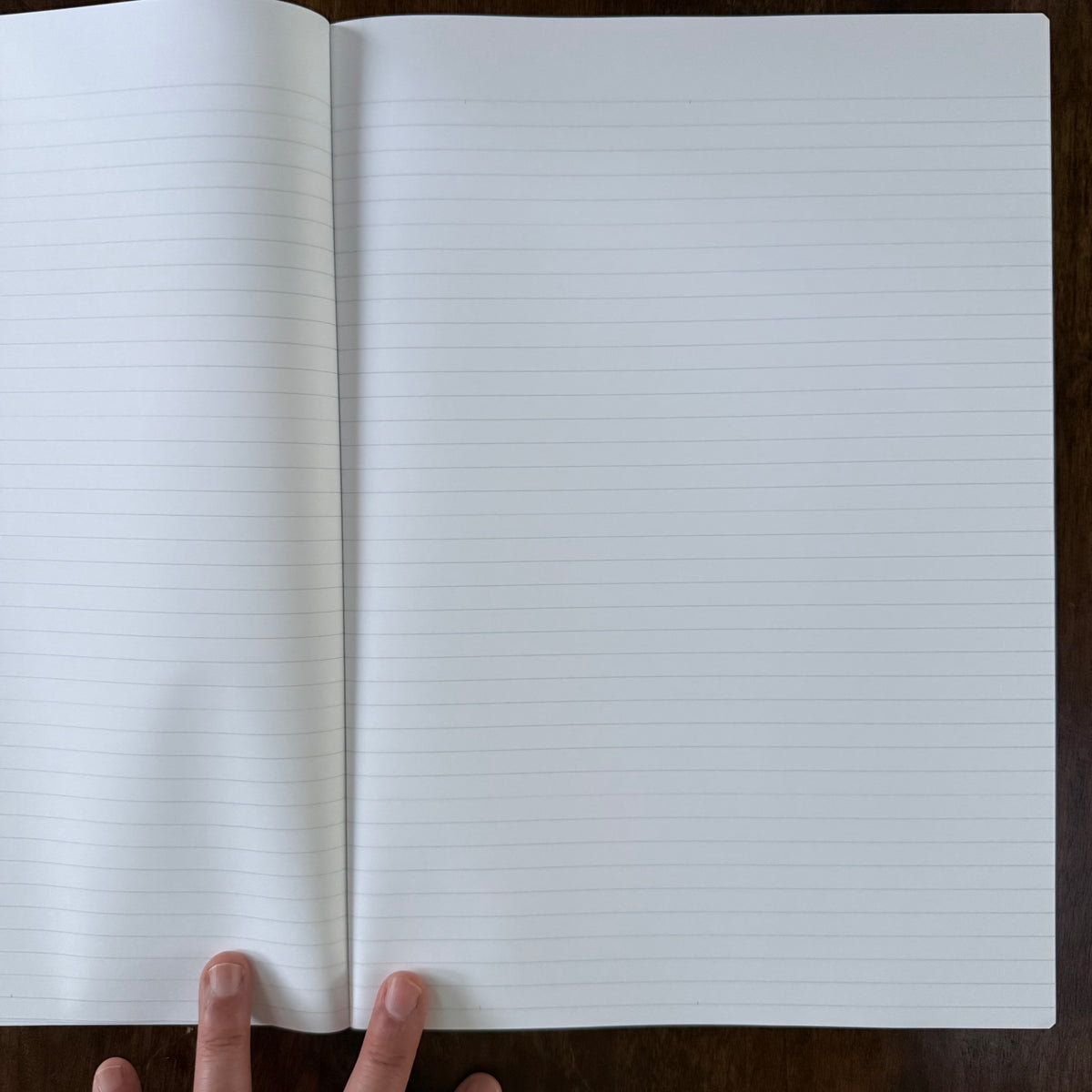 MARK’S EDiT A4 notebook held open on a wooden surface, showing a two-page spread with light gray 7 mm ruled lines.