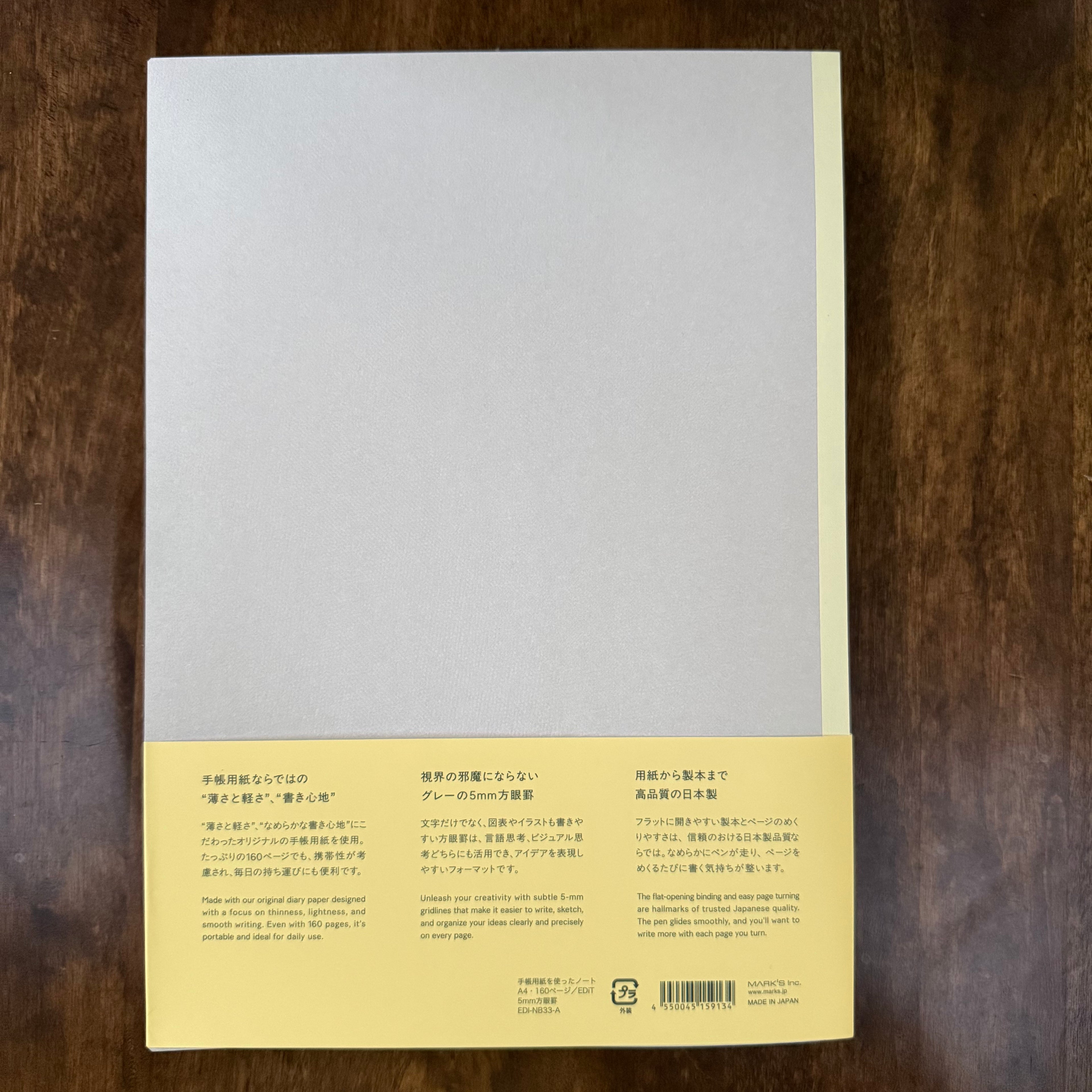 Back of the MARK’S EDiT A5 notebook with a pale gray cover, light yellow spine, and yellow paper band displaying product information and barcode.