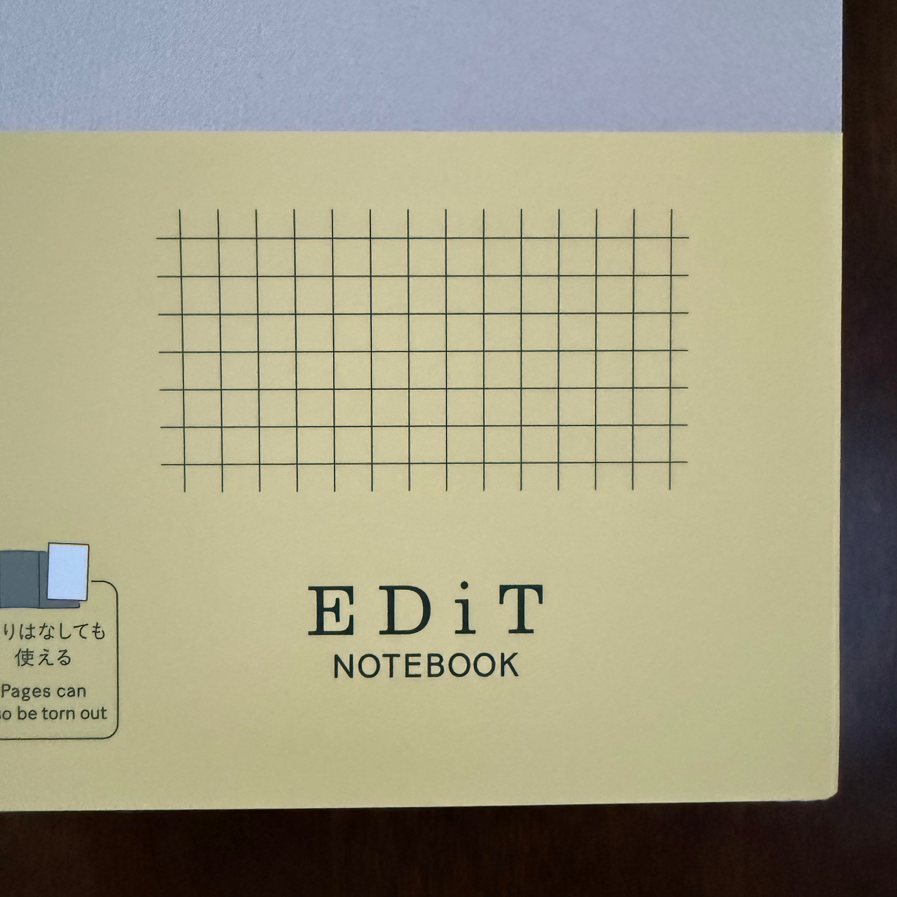 Close-up of the yellow paper band on the MARK’S EDiT notebook, showing the EDiT logo and printed grid illustration.