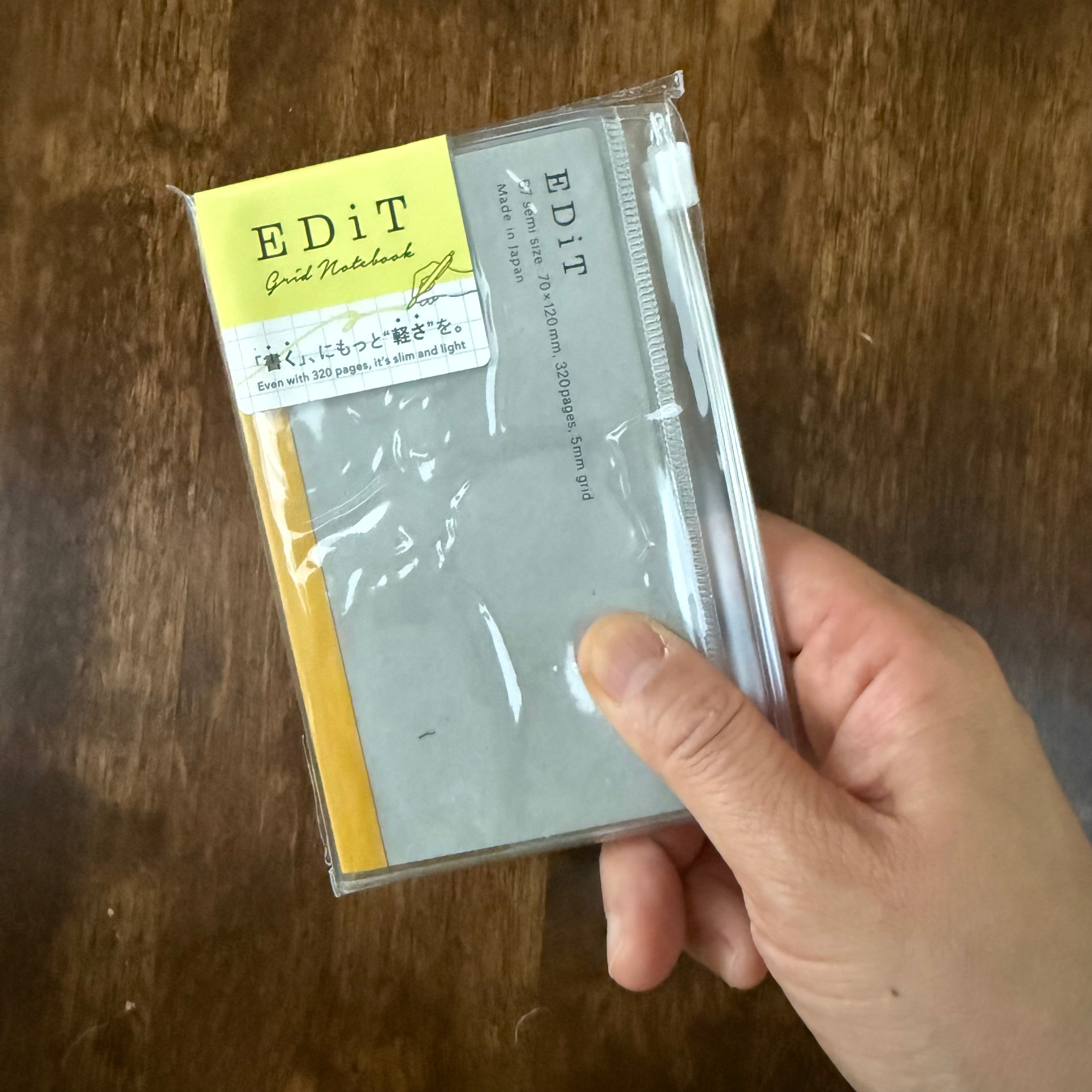MARK’S EDiT B7 Clear notebook held in one hand, showing its compact size and slide-zip pocket cover.