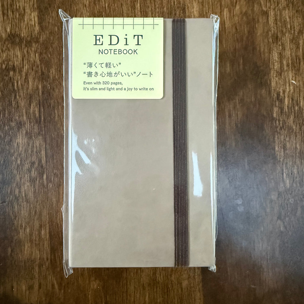 MARK’S EDiT B7 Light Latte notebook in clear packaging, with a brown elastic closure and a label identifying its 320 pages.
