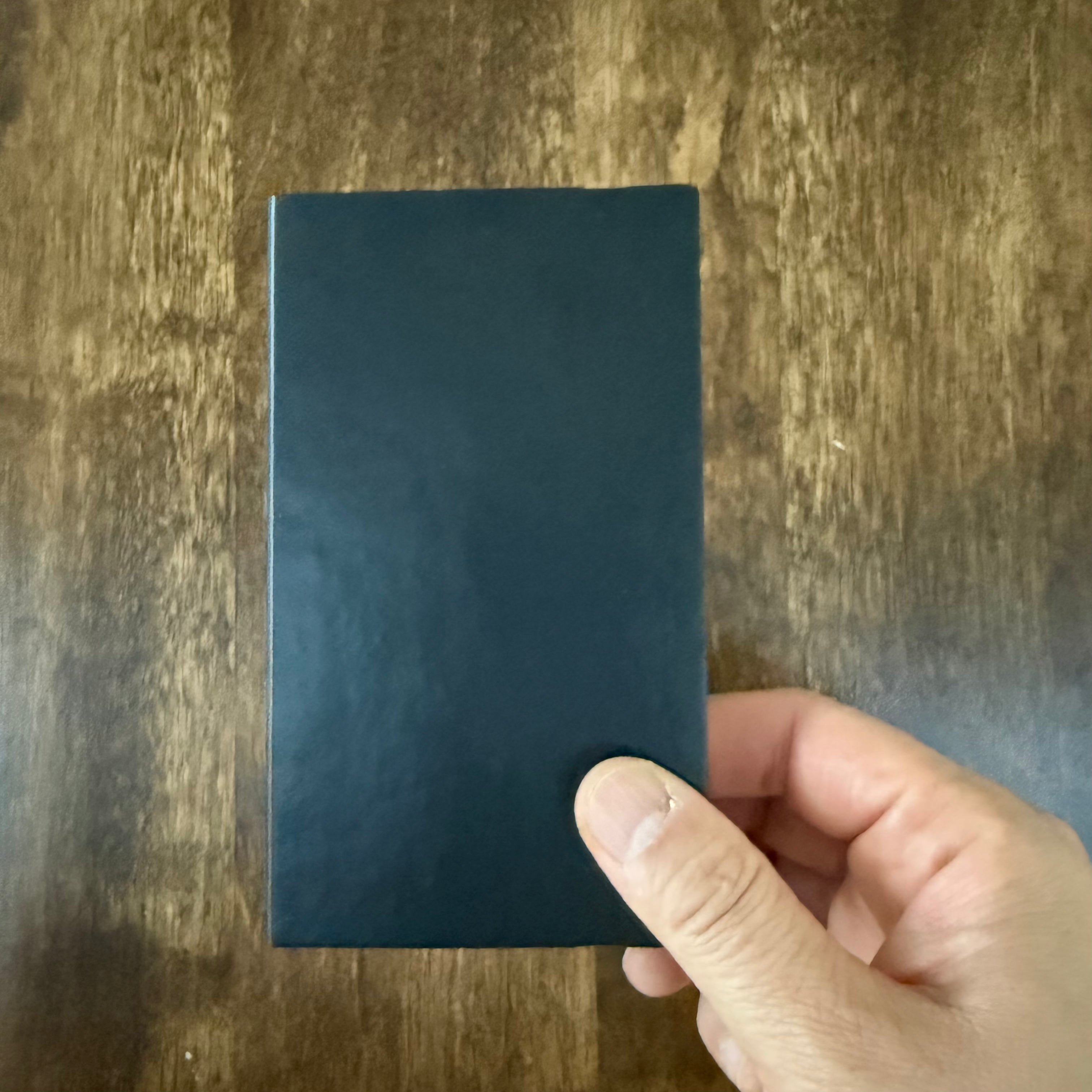 MARK’S EDiT B7 Midnight Black notebook held in one hand, showing its compact size and plain cover.