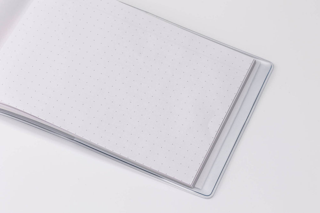 Close-up of the white dot-grid pages in a MARK'S Storage.it Desk notebook, shown inside a clear cover