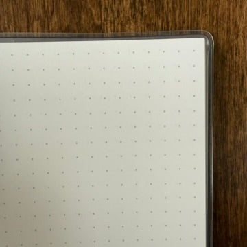 Close-up of the MARK'S Storage.it Desk notebook's pale dot-grid paper and clear cover edge