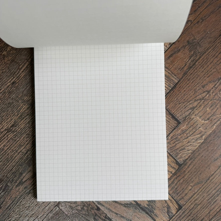 Open Maruman Mnemosyne A5 notepad showing a white page with a pale 5 mm grid