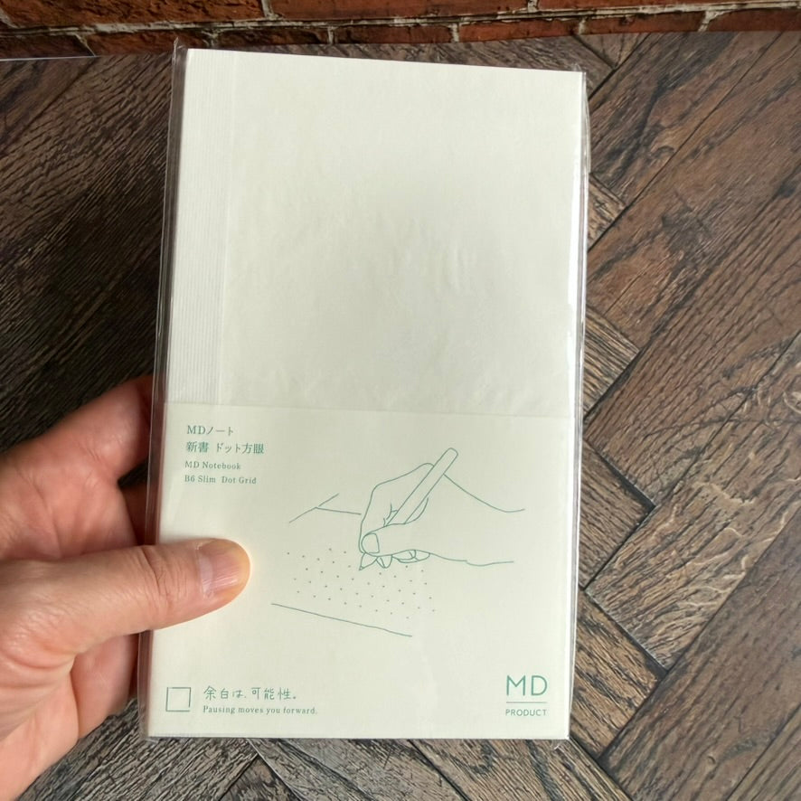 Hand holding the Midori MD B6 Slim dot grid notebook to show its slim paperback size