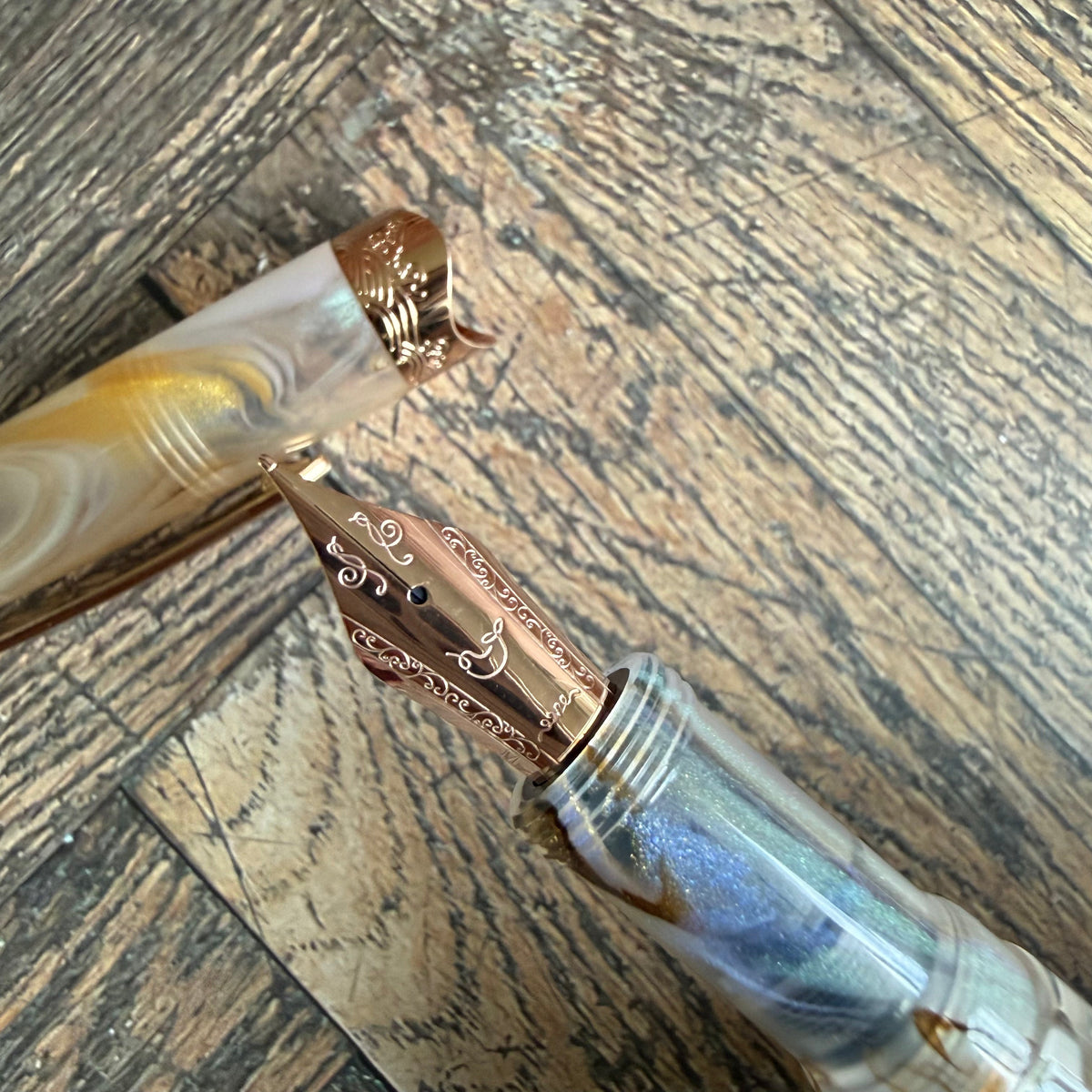 Close-up of the engraved rose gold No. 6 steel nib on the Nahvalur Horizon Pearl beside its pearlescent cap