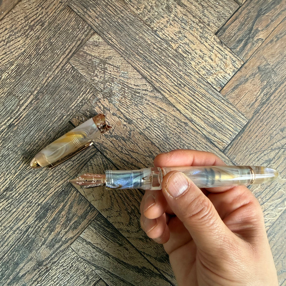 Nahvalur Horizon Pearl fountain pen held uncapped to show the nib, grip and translucent barrel