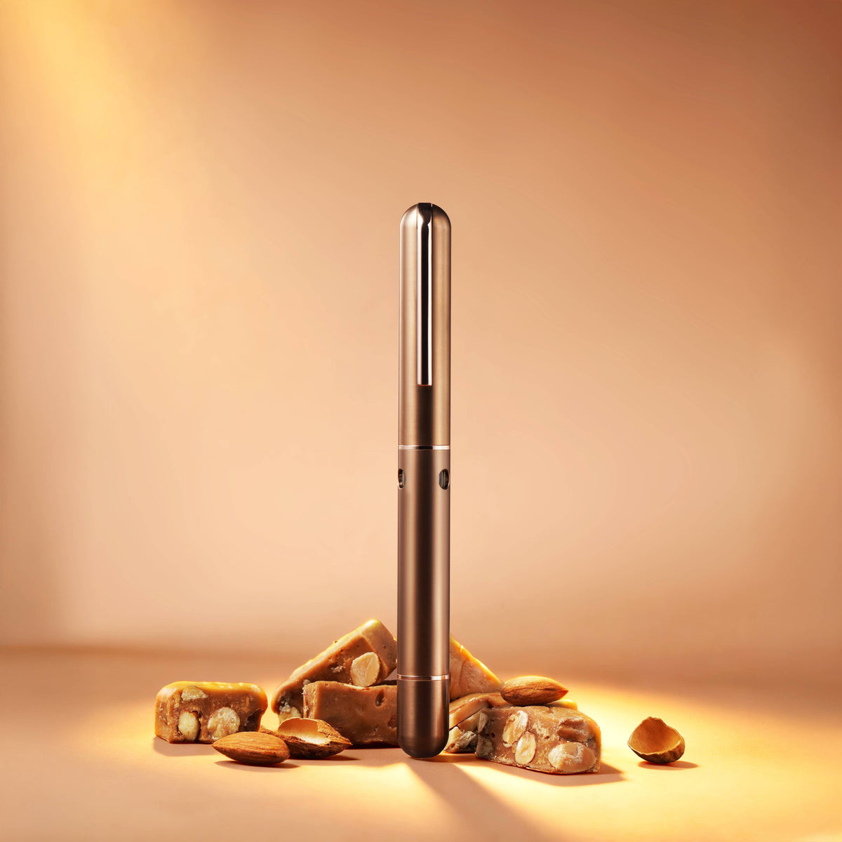 Nahvalur Nautilus Ti Toffee fountain pen capped, standing upright beside toffee pieces