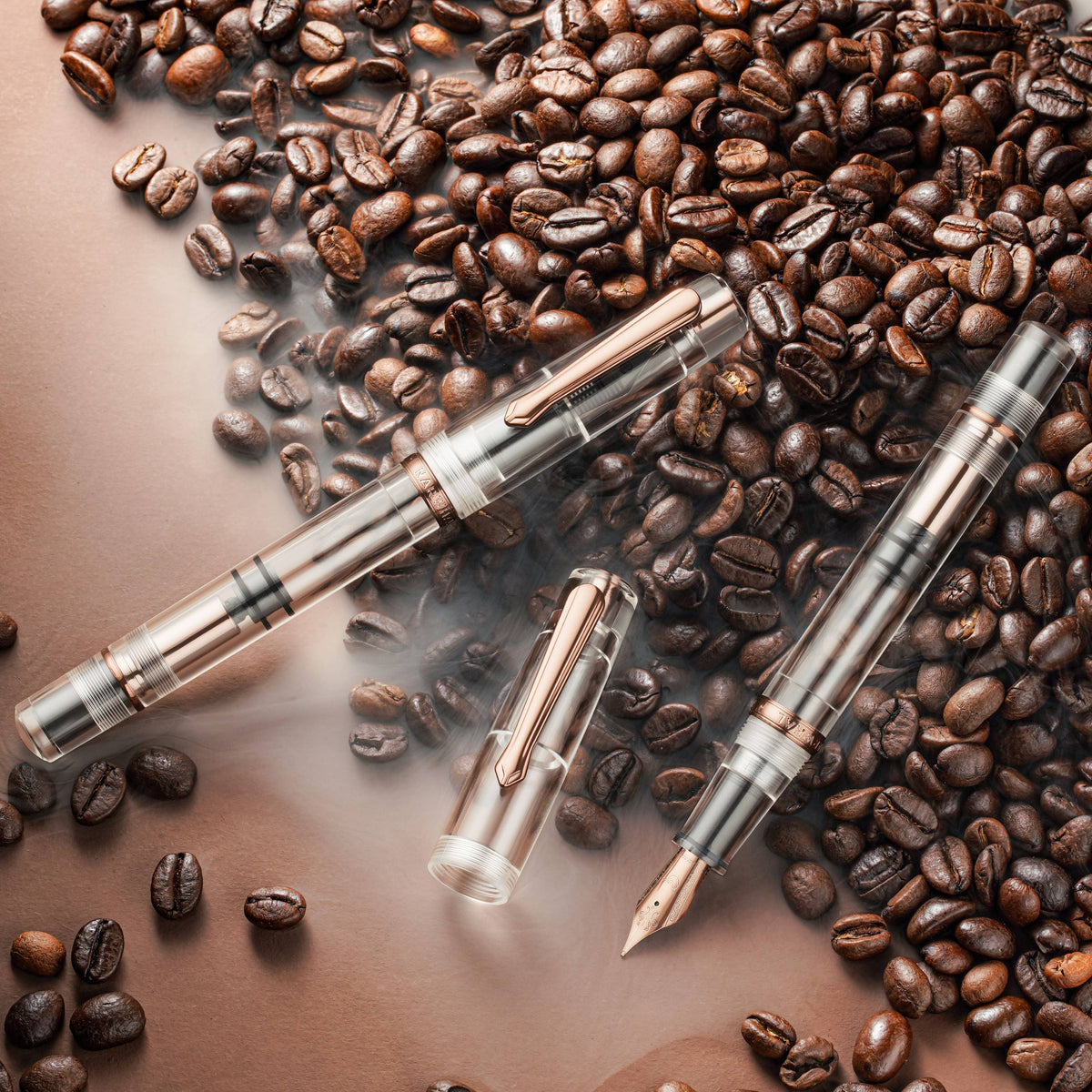 Two Nahvalur Original Fall clear fountain pens and a cap on coffee beans
