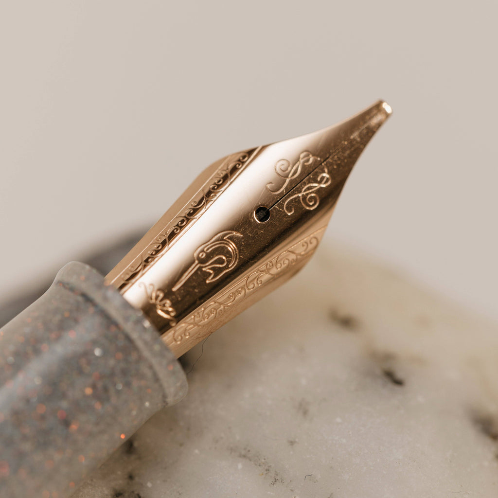 Side view of the engraved rose gold Nahvalur fountain pen nib and shimmering grip section